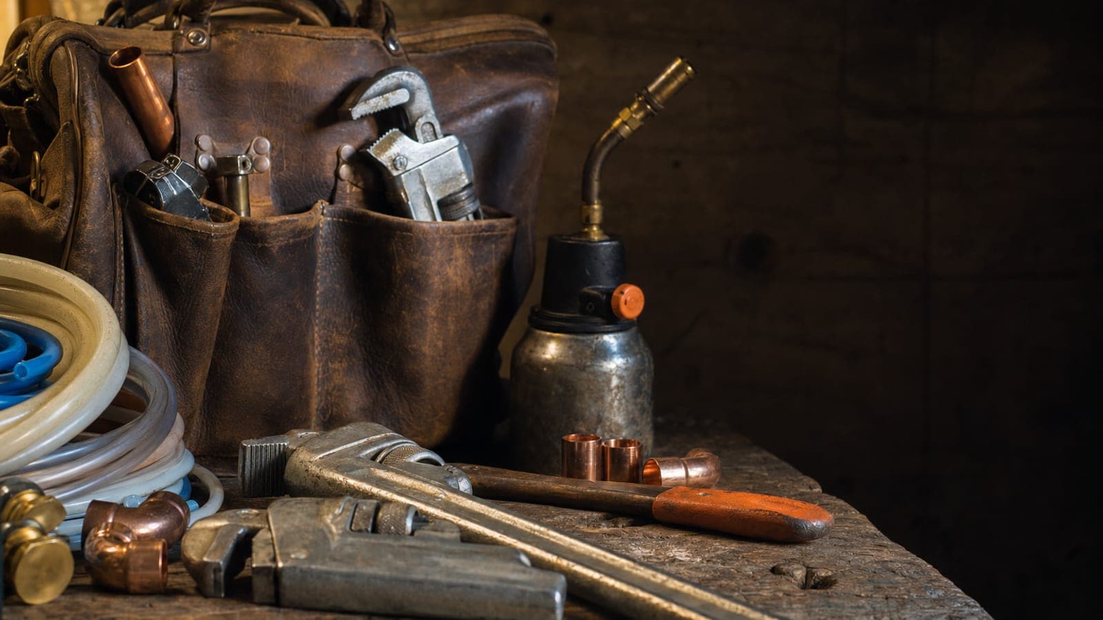 Plumbing tools laid out on a workbench in warm afternoon light